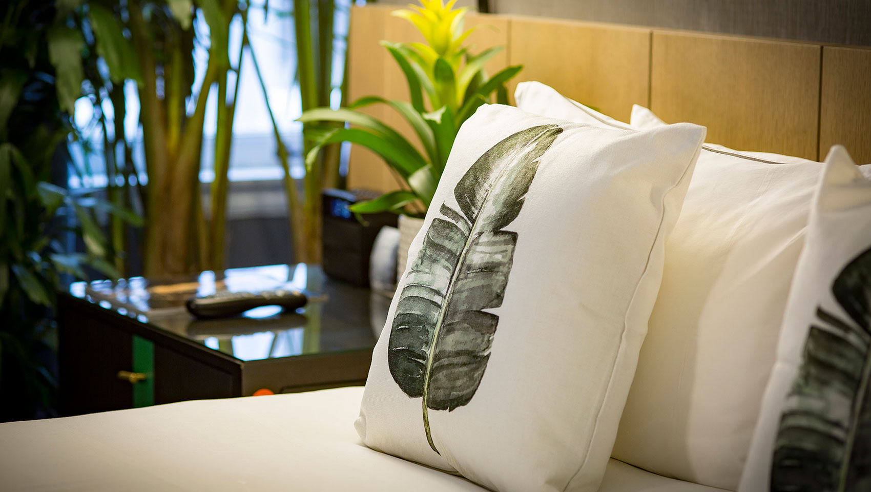 throw pillow on bed with picture of palm leaf