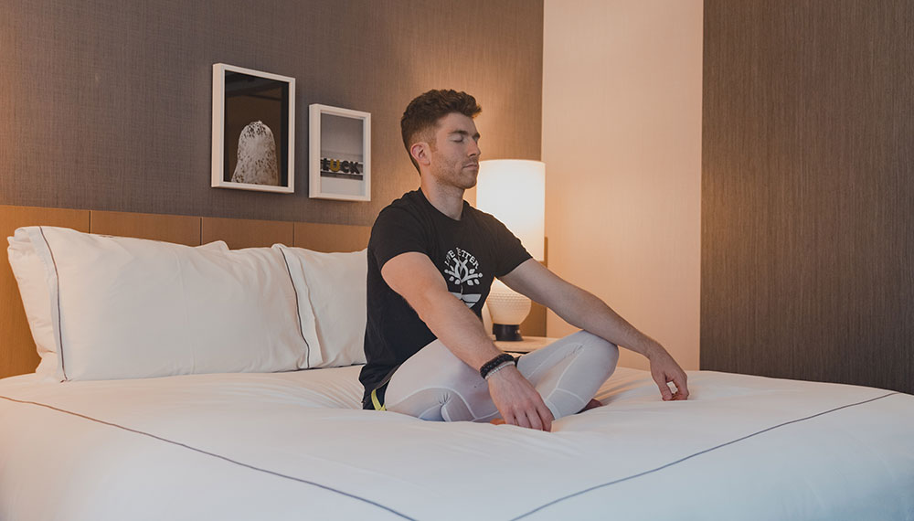 man meditating on bed