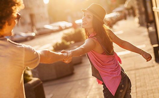 Woman pulling man’s hand on street